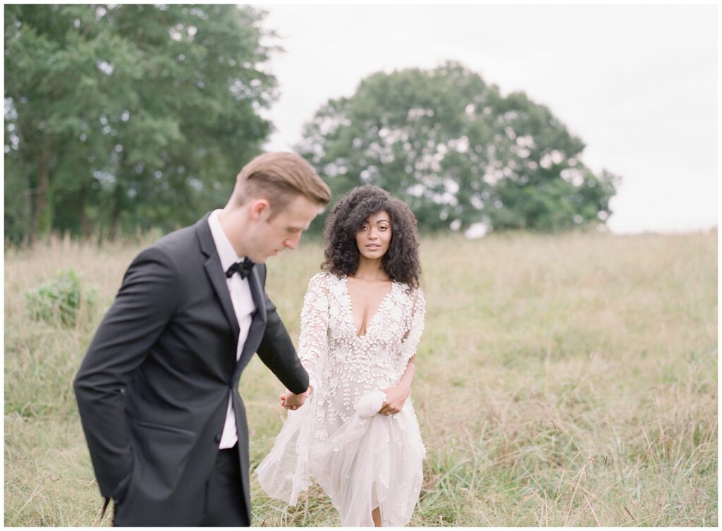 bride and groom holding hands walking in a field of tall grass